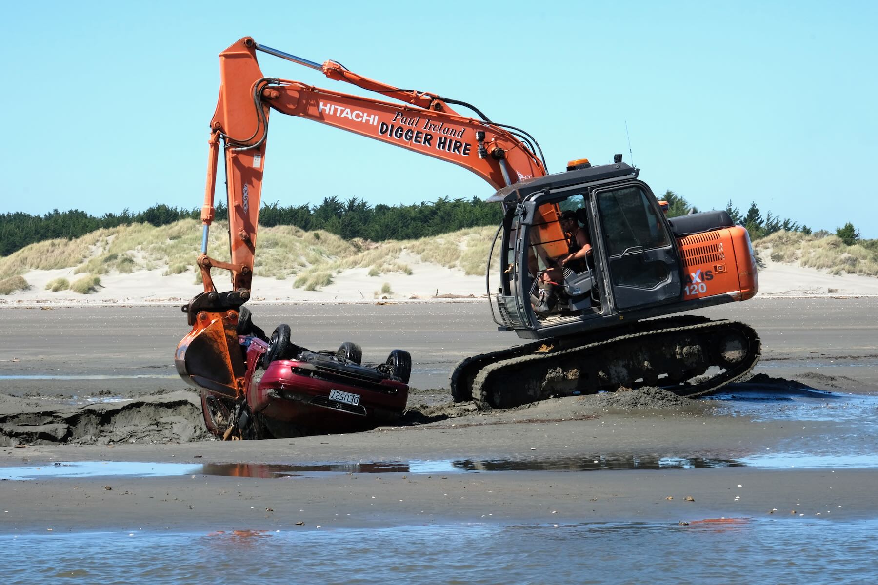 Digger removes abandoned car stuck in the sand, December 2020